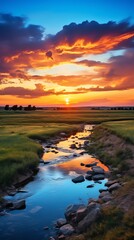 A river flows through a grassy plain at sunset.