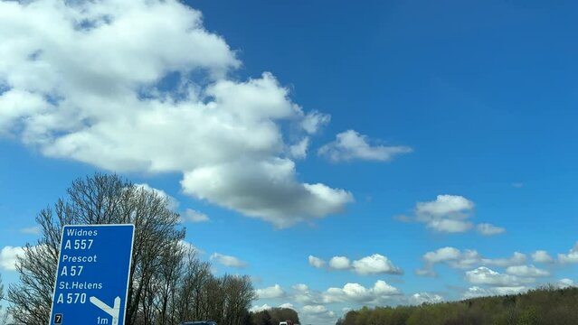 Driving on motorway M62 at J7 towards Liverpool in springtime, car tops, background, driving plate.