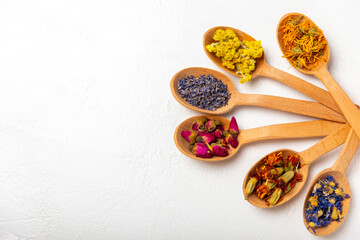 Assortment of dry herbal and berry tea in wooden spoons on a wooden background.Medicinal Healing herbs.Alternative medicine concept.Linden, calendula, cornflowers, marigold, tansy, tea rose.dry herbal © Avocado_studio