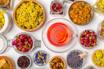 Assortment of dry herbal and berry tea and a cup of tea on a wooden background.Medicinal Healing herbs.Alternative medicine concept.Linden, calendula, cornflowers, marigold, tansy, tea rose.dry herbal