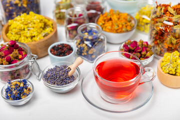Assortment of dry herbal and berry tea and a cup of tea on a wooden background.Medicinal Healing herbs.Alternative medicine concept.Linden, calendula, cornflowers, marigold, tansy, tea rose.dry herbal