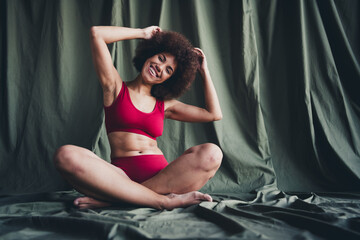 Full size photo of nice lady sit floor crossed legs dressed red lingerie green studio background no filter self acceptance all body perfect