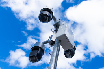 Video surveillance and monitoring of law and order on city streets. Large outdoor CCTV cameras mounted on a pole against the blue sky. Street video surveillance.