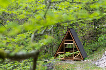 Wooden gazebo for relaxing in a beautiful forest. Wooden gazebo house in a green forest. Glamping.