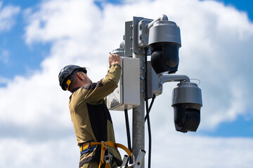 A specialist installs street video surveillance on a pole. Installation and maintenance of outdoor CCTV cameras. CCTV cameras on the city street.