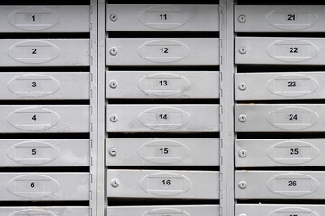 Modern black mailboxes with numbers in the lobby of a residential or office building. Mail boxes with overflowing documents and bills. Mailboxes for letters and correspondence.