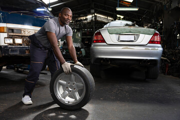 mechanic holding and pushing a tire for fixing in garage
