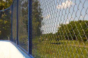 A close-up shot of a blue chain link fence of sports ground in a park