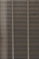 A vertical metal grill in silver with narrow horizontal strips, repatitive pattern, background.