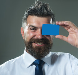 Smiling bearded man covering eye with blank mockup empty business contact card. Handsome...