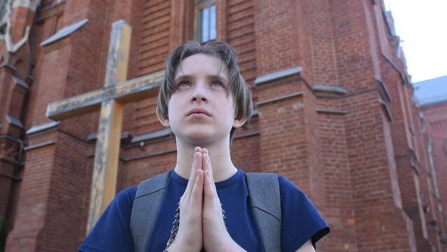 An 11 year old boy prays in front of a Catholic church