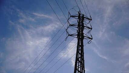 silhouette of metallic electric tower against cloudy sky
