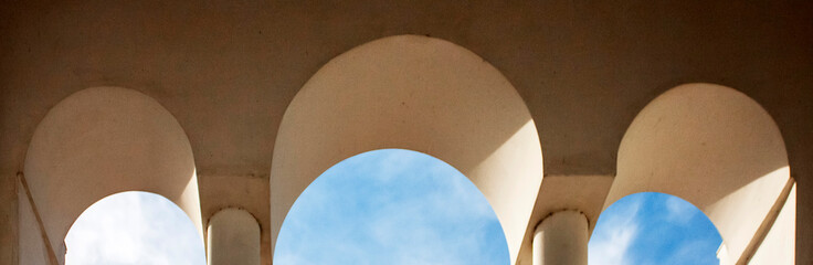 Three arches, bottom view. Three arched doorways and blue sky with clouds. stone arched windows...