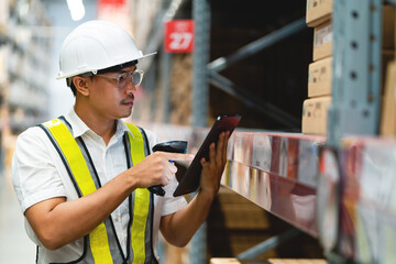 A man in a safety vest is using a tablet to point at something in a warehouse