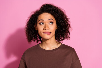 Portrait of pretty young lady bite lip look empty space wear brown t-shirt isolated on pink color...