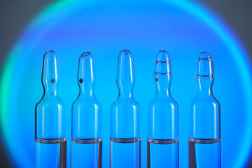 Several ampoules for injection with medicines on a blue background.