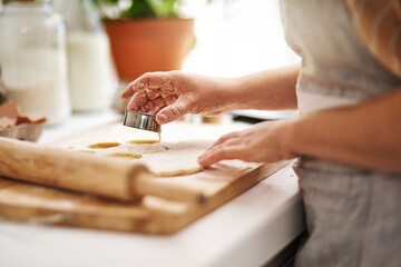 Pastry, hands and woman baking in kitchen for cookies, dessert or biscuits at home with hobby. Food, flour and female person cooking with dough for dish, pie or baker with pin and board at apartment.