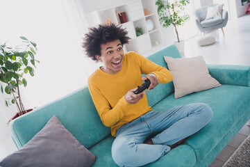 Photo of happy cheerful man sitting divan playing game enjoying weekend rest relax living room...