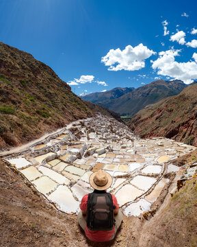 Hiker sitting and admiring the views of the salt mines of Maras in Cusco.