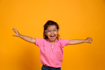 A young child with a bright smile ,The child is wearing a pink shirt and large, clear-rimmed...