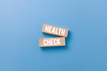 Health check concept with wooden blocks on blue background.