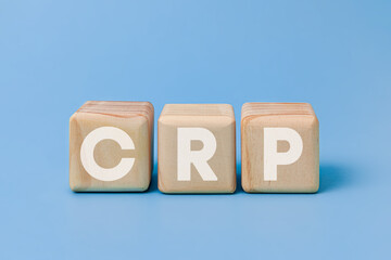 Wooden block on blue background with lettering CRP stands for Medical and C-Reactive Protein test concept