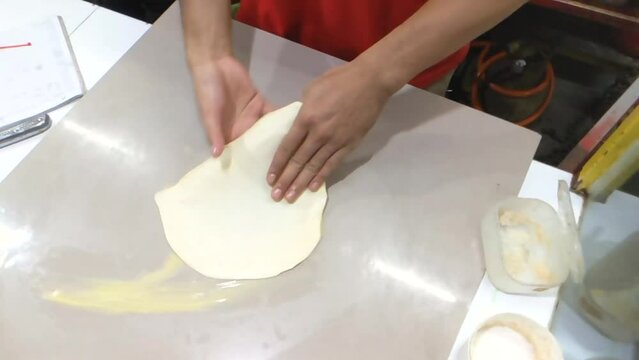 Slow motion of the hands kneading and stretching a pastry dough on the margarine-added surface, emphasizing the tactile and hands-on nature of the process. Perfect for culinary projects or tutorials