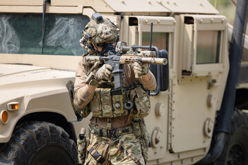 Soldier  in camouflage military uniforms in shooting position  on the side armored fighting car