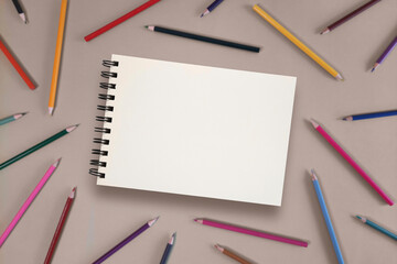 Mockup of open drawing pad with copy space school theme on background of colorful pencils. Selective focus. Space for study and creativity.