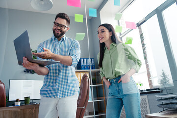 Photo of positive cheerful employers dressed shirts having meeting showing modern device...