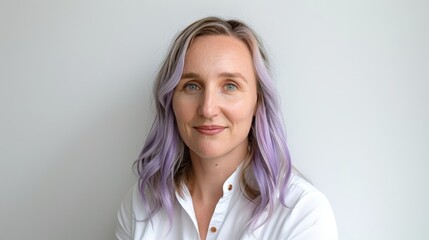 Obraz premium Photo of a Caucasian woman with lavender hair and a white shirt, smiling confidently against a neutral background. The image highlights her modern hairstyle and friendly demeanor.