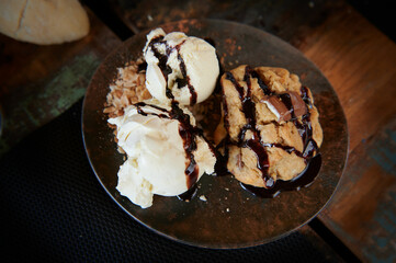 Creamy vanilla ice cream accompanied by a crunchy cookie dipped in hot chocolate sauce