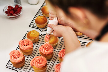 Woman, baker and cupcake in kitchen icing, start up and business with employee for treat or dessert with packaging. Creative, frosting and order preparation for customer, back view and apron