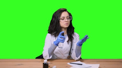 Female doctor in uniform disinfecting hands on the chroma key