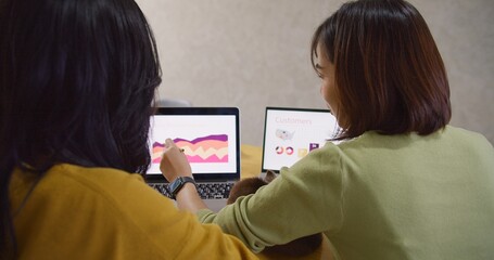 behind view of Two Asian women are working on a presentation together. One of them is pointing at a...