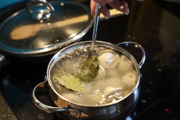 Making dinner at home. Cooking pelmeni in saucepan with boiling water in domestic kitchen. Photo...