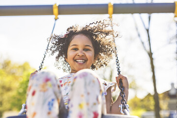 Happy 4 years old girl on a swing. Happy kid on playground