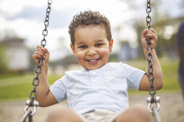 Happy 3 years old girl on a swing. Happy kid on playground