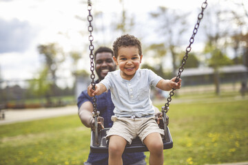 Playtime Moments. father With Her son Swinging Having Fun on the Playground Outside, Sharing...