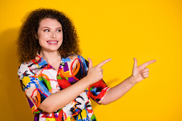 Photo of lovely young lady look point cheerful empty space dressed stylish colorful print garment isolated on yellow color background