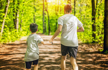 Obraz premium A father and son exercising and jogging together at an outdoor park having great fun