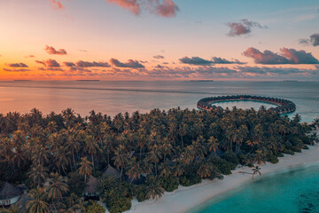 Aerial sunset beautiful Maldives paradise tropical beach. Amazing colorful sea sky bay water, palm trees sandy beach. Luxury villas resort, travel vacation destination. Best popular tourism landscape 