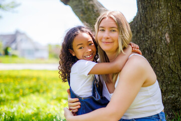 Fototapeta premium Black American child is playing with her mother while having a summer picnic in the public park.