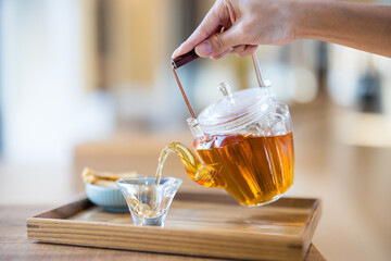 Tea pour into the glass of cup in the cafe shop