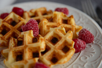 Waffles with raspberries. Tasty waffles with raspberries on a plate, closeup.
