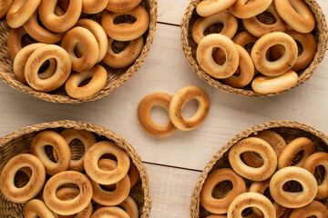 Several tasty bagels in straw plates on a wooden table, close-up, top view.