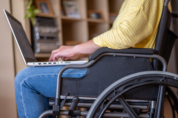 Disabled Or Reduced Mobility Businessperson In A Wheelchair Working From Home Using His Laptop To Surf The Internet Or Make New Business Strategies.Inclusive Workplace