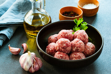 Raw ground meat meatballs in black bowl