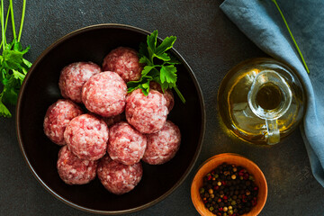 Raw ground meat meatballs in black bowl