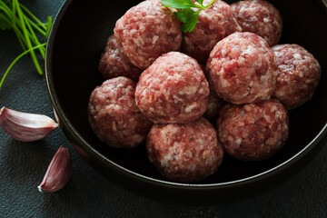 Raw ground meat meatballs in black bowl